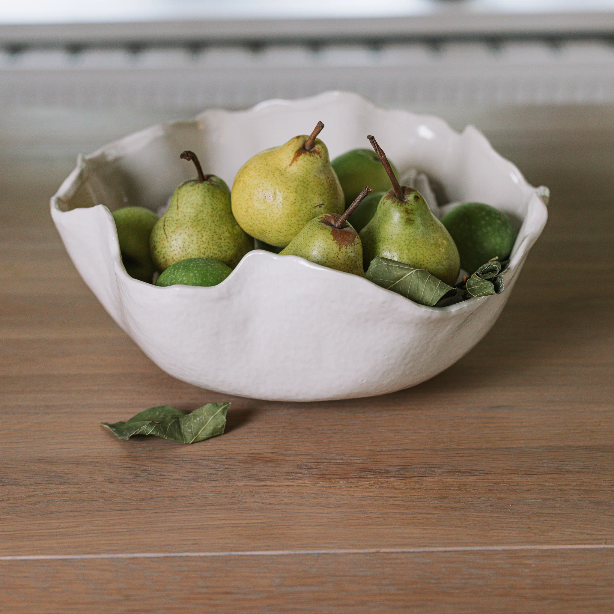 A wooden tray with a ceramic mug, fresh herbs and a small bowl of fruit on a light morning table